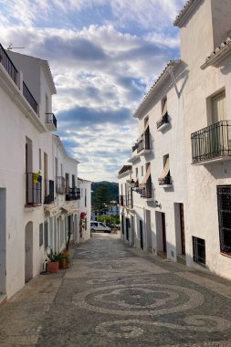 FRIGILIANA, SPAIN - 10 Mayıs 2025: Frigiliana, İspanya 'da beyazlatılmış evler ve renkli çiçeklerle çevrili büyüleyici dar sokaklarda huzurlu bir yürüyüş