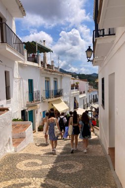 FRIGILIANA, SPAIN - 10 Mayıs 2025: Frigiliana, İspanya 'da beyazlatılmış evler ve renkli çiçeklerle çevrili büyüleyici dar sokaklarda huzurlu bir yürüyüş