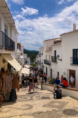 FRIGILIANA, SPAIN - 10 Mayıs 2025: Frigiliana, İspanya 'da beyazlatılmış evler ve renkli çiçeklerle çevrili büyüleyici dar sokaklarda huzurlu bir yürüyüş