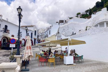 FRIGILIANA, SPAIN - 10 Mayıs 2025: Frigiliana, İspanya 'da beyazlatılmış evler ve renkli çiçeklerle çevrili büyüleyici dar sokaklarda huzurlu bir yürüyüş