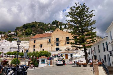 FRIGILIANA, SPAIN - 10 Mayıs 2025: Frigiliana, İspanya 'da beyazlatılmış evler ve renkli çiçeklerle çevrili büyüleyici dar sokaklarda huzurlu bir yürüyüş