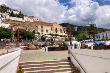 FRIGILIANA, SPAIN - 10 Mayıs 2025: Frigiliana, İspanya 'da beyazlatılmış evler ve renkli çiçeklerle çevrili büyüleyici dar sokaklarda huzurlu bir yürüyüş