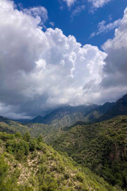 İspanya 'nın Frigiliana kentindeki eski bir sulama hendeği boyunca bir yürüyüş yolundan çevresindeki dağların ve resimli köyün manzarası..