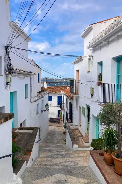 FRIGILIANA, SPAIN - 10 Mayıs 2025: Frigiliana, İspanya 'da beyazlatılmış evler ve renkli çiçeklerle çevrili büyüleyici dar sokaklarda huzurlu bir yürüyüş