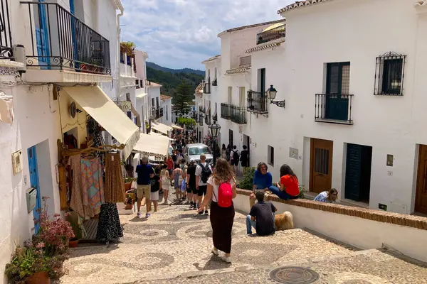 FRIGILIANA, SPAIN - 10 Mayıs 2025: Frigiliana, İspanya 'da beyazlatılmış evler ve renkli çiçeklerle çevrili büyüleyici dar sokaklarda huzurlu bir yürüyüş