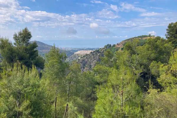 İspanya 'nın Frigiliana kentindeki eski bir sulama hendeği boyunca bir yürüyüş yolundan çevresindeki dağların ve resimli köyün manzarası..