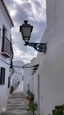 FRIGILIANA, SPAIN - 10 Mayıs 2025: Frigiliana, İspanya 'da beyazlatılmış evler ve renkli çiçeklerle çevrili büyüleyici dar sokaklarda huzurlu bir yürüyüş