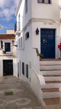 FRIGILIANA, SPAIN - 10 Mayıs 2025: Frigiliana, İspanya 'da beyazlatılmış evler ve renkli çiçeklerle çevrili büyüleyici dar sokaklarda huzurlu bir yürüyüş