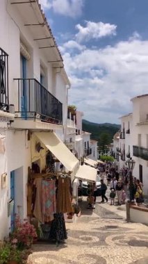 FRIGILIANA, SPAIN - 10 Mayıs 2025: Frigiliana, İspanya 'da beyazlatılmış evler ve renkli çiçeklerle çevrili büyüleyici dar sokaklarda huzurlu bir yürüyüş