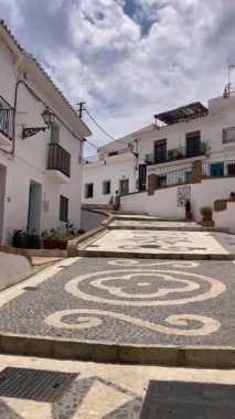 FRIGILIANA, SPAIN - 10 Mayıs 2025: Frigiliana, İspanya 'da beyazlatılmış evler ve renkli çiçeklerle çevrili büyüleyici dar sokaklarda huzurlu bir yürüyüş