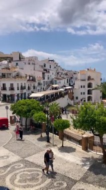 FRIGILIANA, SPAIN - 10 Mayıs 2025: Frigiliana, İspanya 'da beyazlatılmış evler ve renkli çiçeklerle çevrili büyüleyici dar sokaklarda huzurlu bir yürüyüş