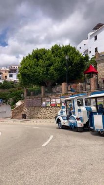 FRIGILIANA, SPAIN - 10 Mayıs 2025: Frigiliana, İspanya 'da beyazlatılmış evler ve renkli çiçeklerle çevrili büyüleyici dar sokaklarda huzurlu bir yürüyüş