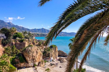 NERJA, İspanya - 22 Mart 2025: Işıldayan deniz ve büyüleyici şehrin muhteşem manzaraları, 22 Mart 2025 tarihinde İspanya 'nın Nerja kentinde nefes kesen kıyı manzaraları ve pitoresk bir atmosfer sunuyor.