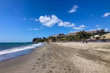 NERJA, İspanya - 22 Mart 2025: Işıldayan deniz ve büyüleyici şehrin muhteşem manzaraları, 22 Mart 2025 tarihinde İspanya 'nın Nerja kentinde nefes kesen kıyı manzaraları ve pitoresk bir atmosfer sunuyor.