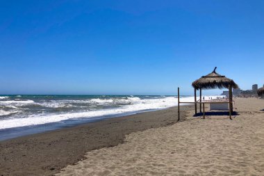 TORREMOLINOS, SPAIN - 30 Nisan 2025: Canlı şehir merkezinden manzaralı deniz geçidine doğru sakin bir yürüyüş yapmak, İspanya 'nın Torremolinos kentindeki büyüleyici sahil atmosferinde ıslanmak.