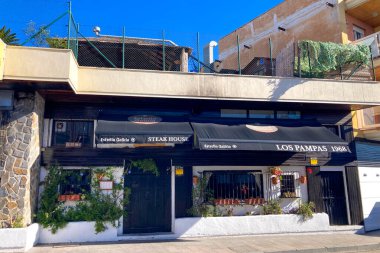 TORREMOLINOS, SPAIN - 30 Nisan 2025: Canlı şehir merkezinden manzaralı deniz geçidine doğru sakin bir yürüyüş yapmak, İspanya 'nın Torremolinos kentindeki büyüleyici sahil atmosferinde ıslanmak.