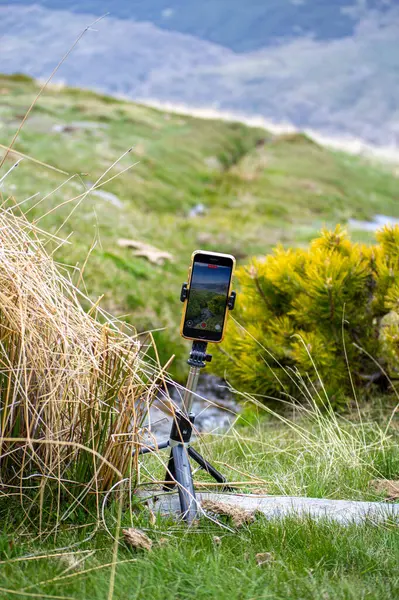 SIERRA NEVADA, İspanya - 18 Mayıs 2025: Tripodun üzerindeki Iphone ilkbaharda eriyen kardan akan su akışını filme alıyor, Sierra Nevada aralığı, Endülüs, İspanya