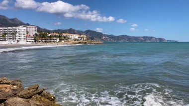 NERJA, İspanya - 22 Mart 2025: Işıldayan deniz ve büyüleyici şehrin muhteşem manzaraları, 22 Mart 2025 tarihinde İspanya 'nın Nerja kentinde nefes kesen kıyı manzaraları ve pitoresk bir atmosfer sunuyor.