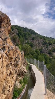 İspanya 'nın Frigiliana kentindeki eski bir sulama hendeği boyunca bir yürüyüş yolundan çevresindeki dağların ve resimli köyün manzarası..