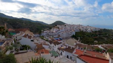 FRIGILIANA, SPAIN - 10 Mayıs 2025: Frigiliana, İspanya 'da beyazlatılmış evler ve renkli çiçeklerle çevrili büyüleyici dar sokaklarda huzurlu bir yürüyüş