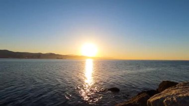 İspanya 'nın Malaga kentindeki plajı ve manzarayı aydınlatan altın bir gün doğumu sakin ve pitoresk bir kıyı manzarası yaratır..