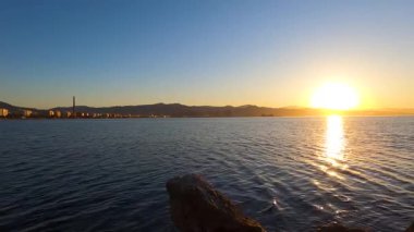 İspanya 'nın Malaga kentindeki plajı ve manzarayı aydınlatan altın bir gün doğumu sakin ve pitoresk bir kıyı manzarası yaratır..