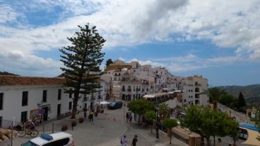 FRIGILIANA, SPAIN - 10 Mayıs 2025: Frigiliana, İspanya 'da beyazlatılmış evler ve renkli çiçeklerle çevrili büyüleyici dar sokaklarda huzurlu bir yürüyüş