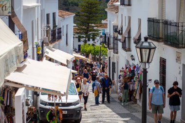 FRIGILIANA, SPAIN - 10 Mayıs 2025: Frigiliana, İspanya 'da beyazlatılmış evler ve renkli çiçeklerle çevrili büyüleyici dar sokaklarda huzurlu bir yürüyüş