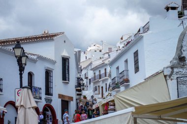 FRIGILIANA, SPAIN - 10 Mayıs 2025: Frigiliana, İspanya 'da beyazlatılmış evler ve renkli çiçeklerle çevrili büyüleyici dar sokaklarda huzurlu bir yürüyüş