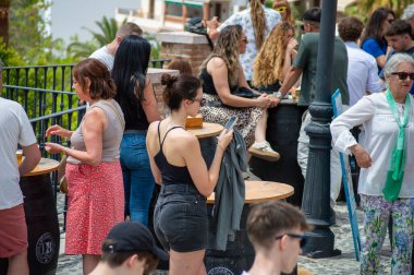 FRIGILIANA, SPAIN - 10 Mayıs 2025: Frigiliana, İspanya 'da beyazlatılmış evler ve renkli çiçeklerle çevrili büyüleyici dar sokaklarda huzurlu bir yürüyüş