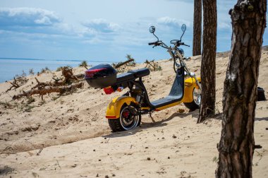KYIV, UKRAINE - 24 Mayıs 2020: Ukrayna 'daki Kiev Denizi' nin kumlu kıyısında bir scooter duruyor, modern ulaşımı kıyı manzarasının doğal güzelliğiyle harmanlıyor