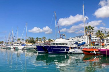 BENALMADENA, SPAIN - 24 Mayıs 2025 İspanya 'nın canlı limanı Benalmadena' da, kıyı cazibesi ve deniz zarafeti ile çevrili demirlemiş yatlar arasında rahatlatıcı bir yürüyüş yapmak.
