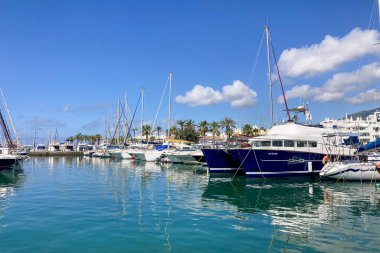 BENALMADENA, SPAIN - 24 Mayıs 2025 İspanya 'nın canlı limanı Benalmadena' da, kıyı cazibesi ve deniz zarafeti ile çevrili demirlemiş yatlar arasında rahatlatıcı bir yürüyüş yapmak.