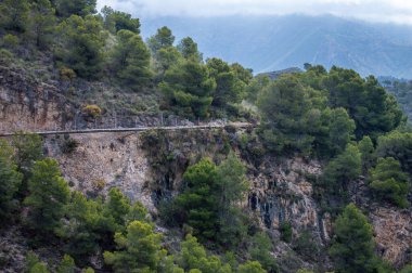 İspanya 'nın Frigiliana kentindeki eski bir sulama hendeği boyunca bir yürüyüş yolundan çevresindeki dağların ve resimli köyün manzarası..