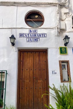 FRIGILIANA, SPAIN - 10 Mayıs 2025: Frigiliana, İspanya 'da beyazlatılmış evler ve renkli çiçeklerle çevrili büyüleyici dar sokaklarda huzurlu bir yürüyüş