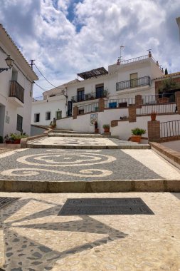 FRIGILIANA, SPAIN - 10 Mayıs 2025: Frigiliana, İspanya 'da beyazlatılmış evler ve renkli çiçeklerle çevrili büyüleyici dar sokaklarda huzurlu bir yürüyüş