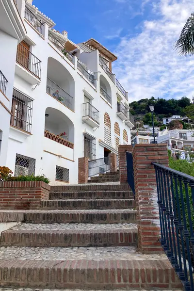 FRIGILIANA, SPAIN - 10 Mayıs 2025: Frigiliana, İspanya 'da beyazlatılmış evler ve renkli çiçeklerle çevrili büyüleyici dar sokaklarda huzurlu bir yürüyüş