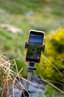 SIERRA NEVADA, İspanya - 18 Mayıs 2025: Tripodun üzerindeki Iphone ilkbaharda eriyen kardan akan su akışını filme alıyor, Sierra Nevada aralığı, Endülüs, İspanya