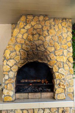 Doğal taştan yapılmış, ızgara yapmak ve toplamak için mükemmel, kırsal bir barbekü şöminesi..