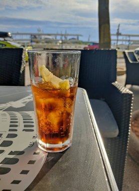 Soğuk bir bardak kola ve limon dilimi açık bir masada oturur, güneşli ve rahat bir atmosferi yakalar rahatlık ve ferahlık için mükemmeldir..