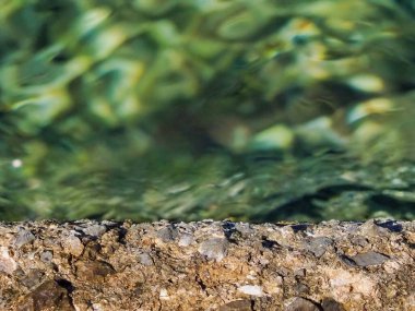 Sade ve berrak suların canlı yeşil arka planına sahip dokulu kayaların detaylı bir yakın çekimi. Doğa temaları, dokular veya sükunet ve huzurla ilgili arka planlar için idealdir..
