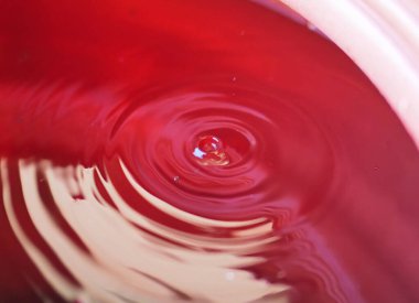 A detailed photograph showcasing the dynamic textures of ripples on a red liquid surface. clipart