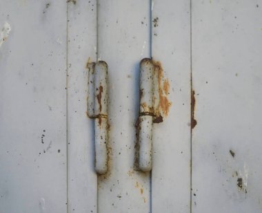 Eski menteşelerin paslanma ve yaşlanma belirtileriyle dolu metal bir yüzeydeki detaylı görüntüsü çürümeyi ve dokusunu gösteriyor..