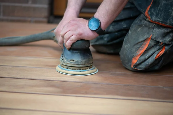 Sanding process of wooden terrace floors. Sanding machine remove imperfections. Rejuvenation and maintenance of outdoor wooden flooring, wood restoration.