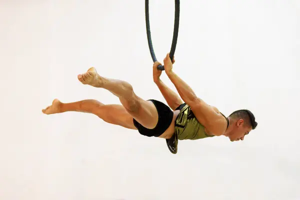 A Mexican male gymnast crafts a solo aerial routine, demonstrating a high level of skill, strength, and concentration in unique and dynamic movements