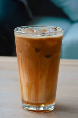 Buzlu karamel latte kahve, arka planda çift duvar yalıtımlı bardaklar. Ferahlatıcı, yaz içkilerinin tadını çıkar.