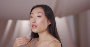 Tüylü güzel Asyalı kız poz veriyor. Açık renk çıplak makyajlı güzel bir kadının yakın plan portresi. Güzel bir bayan kameraya bakıp gülümsüyor. Makyaj konsepti.