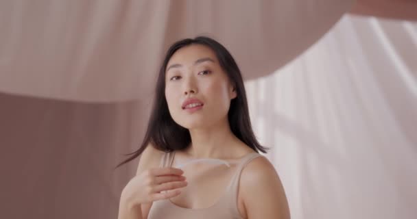 自然美丽的亚洲女性模特 完美的护肤姿势在浅褐色背景的工作室里 迷人的女人带着自然淡淡的裸体妆容 留着羽毛 自然美概念 — 图库视频影像