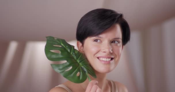 Yaprak Tutan Genç Güzel Bir Kadın Açık Bej Arka Planda — Stok video