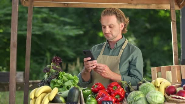 Portret Przystojnego Dojrzałego Męskiego Sprzedawcy Fartuchu Stukającego Smartfona Stojącego Zewnątrz — Wideo stockowe